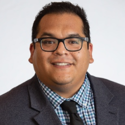 Headshot of male student with glasses and in a suit and tie smiling